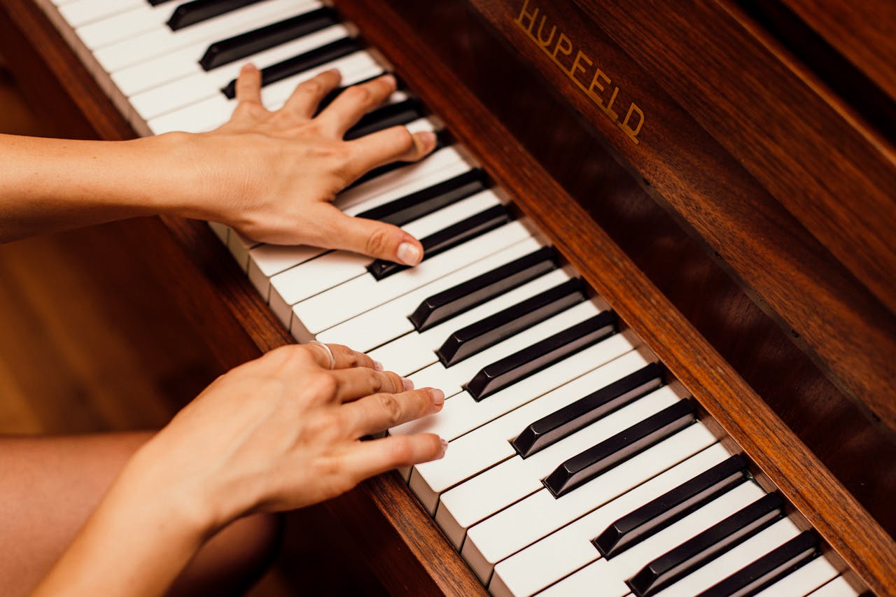 Musician's hands playing wooden piano keys in a high contrast image, capturing musical expression.